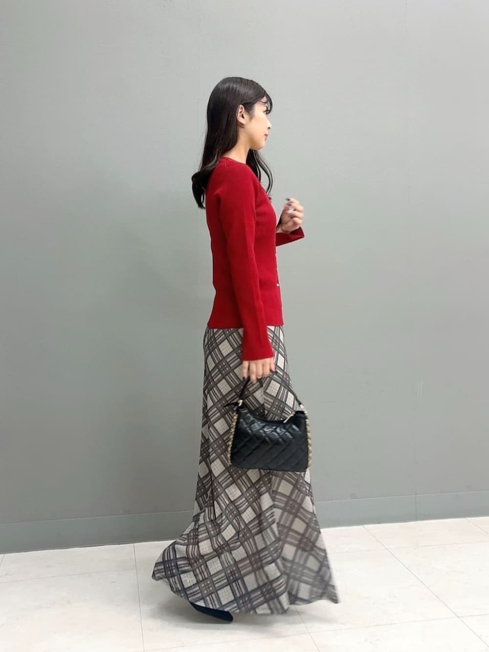 ブラック系のパンプス、レッド系のカーディガン/ボレロ、ベージュ系のスカートを着用したレディースの秋コーディネートの3枚目の写真