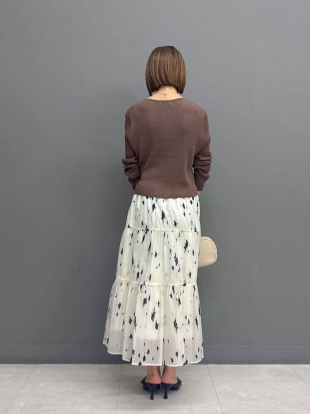 ホワイト系のボストンバッグ、ブラウン系のカーディガン/ボレロ、ホワイト系のスカートを着用したレディースの秋コーディネートの3枚目の写真