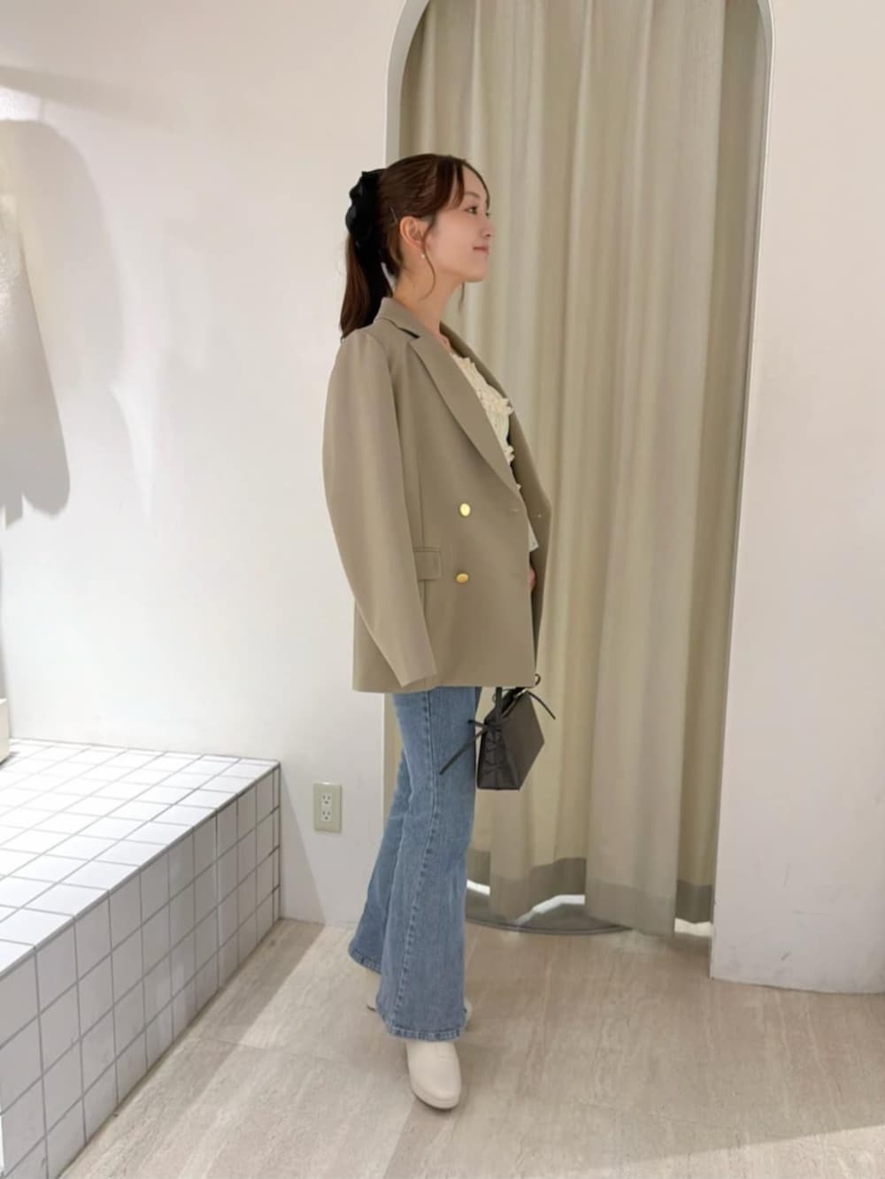 ブルー系のデニムパンツ、ホワイト系のシャツ/ブラウス、ブラウン系のショルダーバッグを着用したレディースの秋コーディネートの3枚目の写真