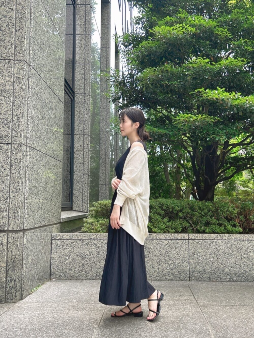 ブラック系のパンプス、ホワイト系のニット/セーター、ブラック系のワンピースを着用したレディースの夏コーディネートの2枚目の写真