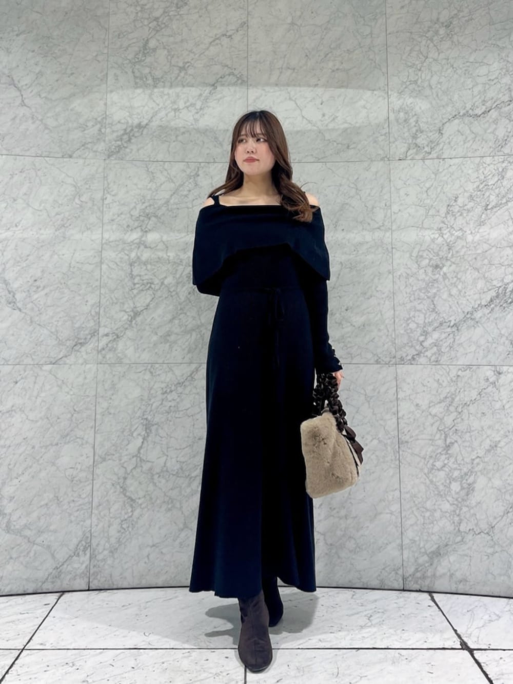 ブラック系のワンピース、ベージュ系のトートバッグを着用したレディースの冬コーディネートの2枚目の写真