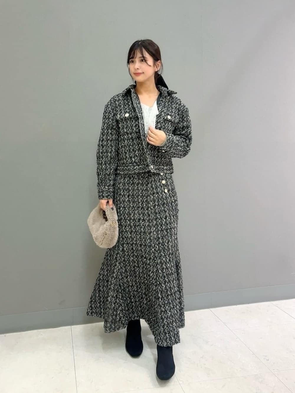 ベージュ系のハンドバッグ、ブラック系のテーラードジャケット、ブラック系のスカートを着用したレディースの秋コーディネートの2枚目の写真