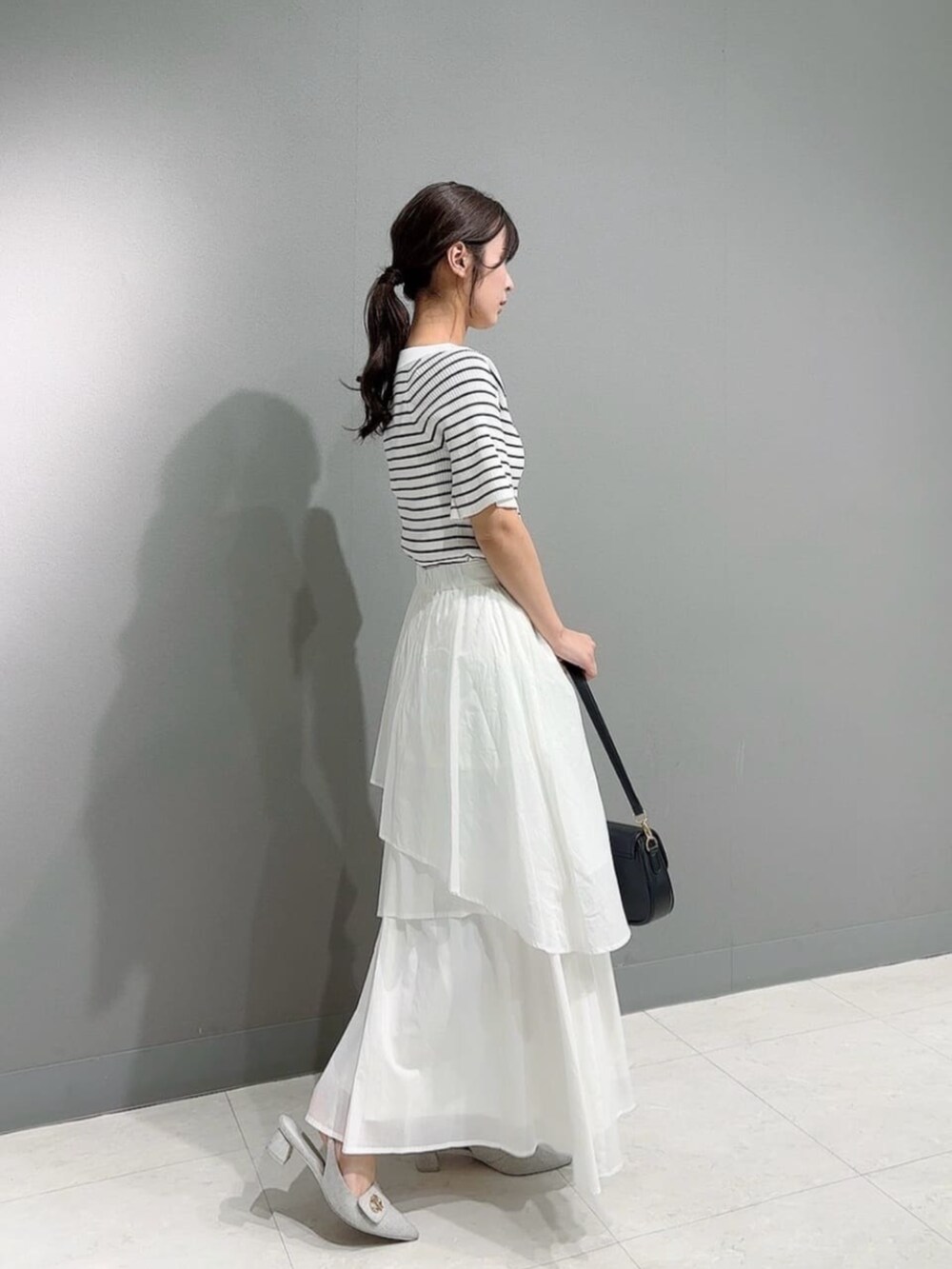 ブラック系のショルダーバッグ、ホワイト系のニット/セーター、ホワイト系のスカートを着用したレディースの春コーディネートの3枚目の写真