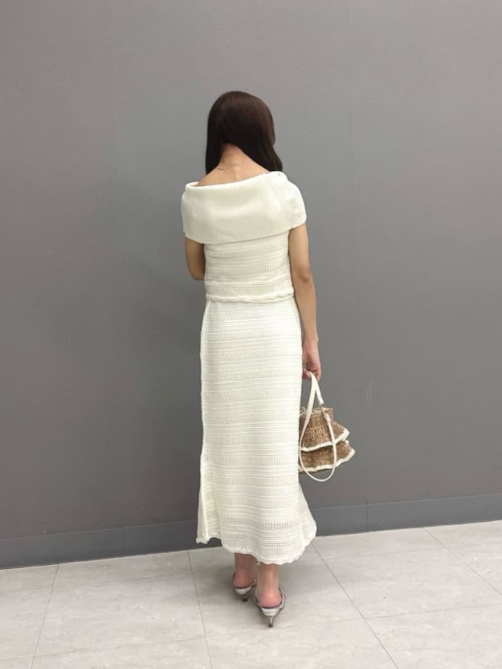 シルバー系のパンプス、ベージュ系のショルダーバッグ、ホワイト系のワンピースを着用したレディースの夏コーディネートの3枚目の写真