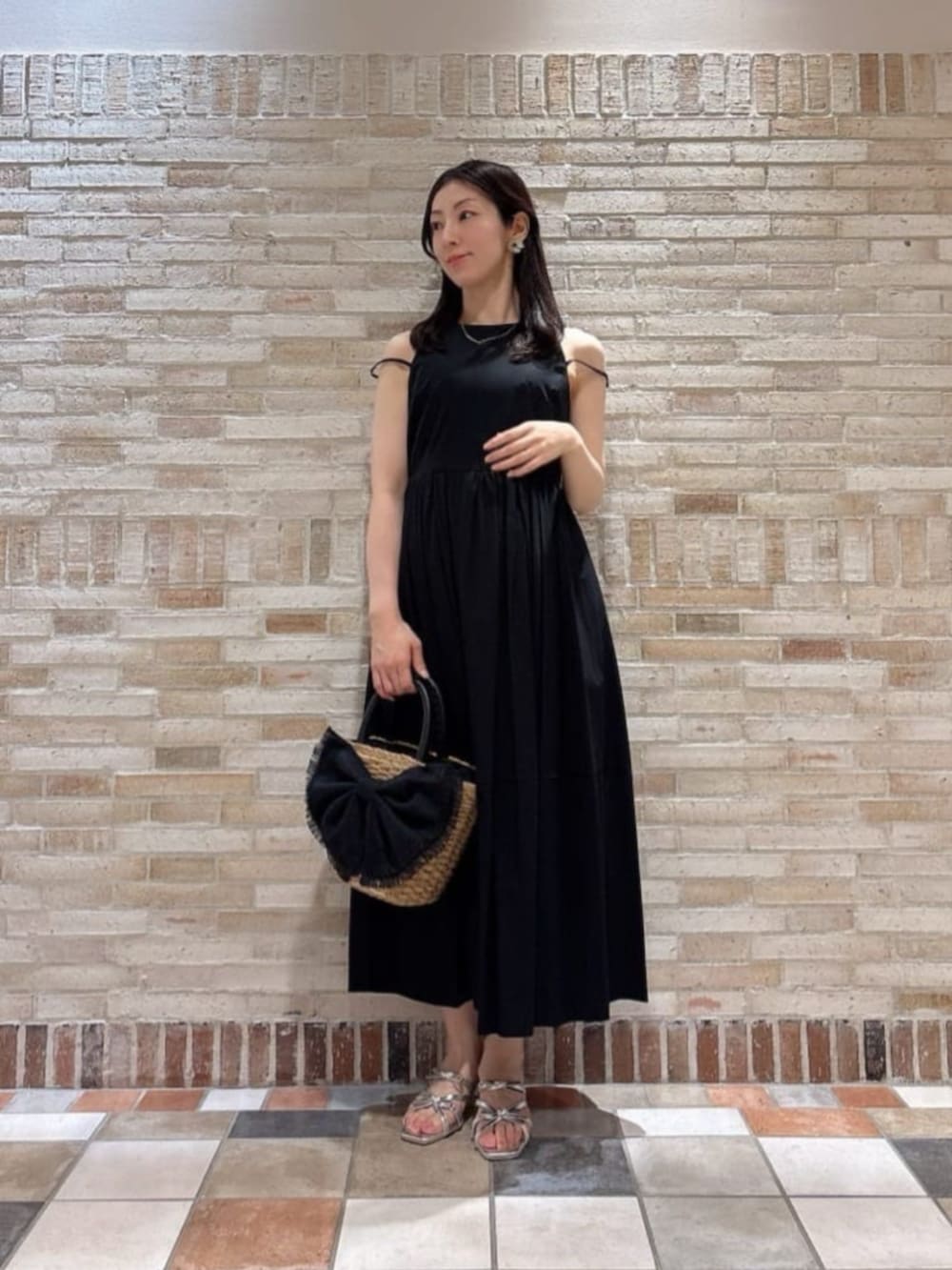 シルバー系のパンプス、ブラック系のワンピース、ブラック系のショルダーバッグを着用したレディースの夏コーディネートの2枚目の写真