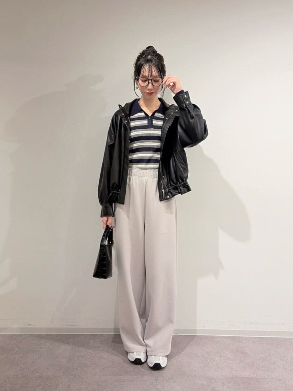 ブラック系のブルゾン、ブルー系のニット/セーター、グレー系のスウェットパンツを着用したレディースの冬コーディネートの2枚目の写真