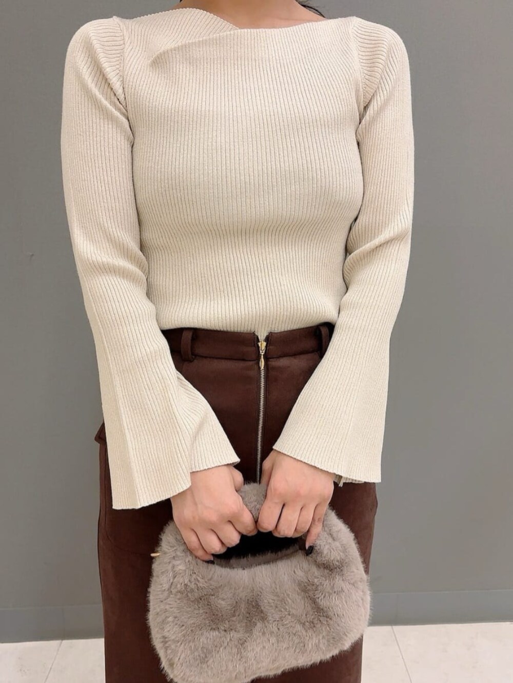 ベージュ系のハンドバッグ、ブラック系のパンプス、ブラウン系のスカートを着用したレディースの秋コーディネートの3枚目の写真