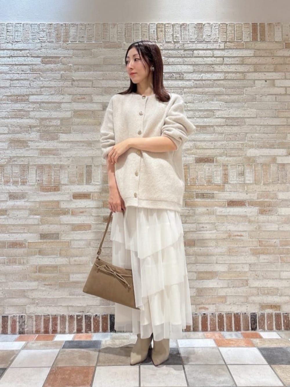 ベージュ系のショルダーバッグ、ホワイト系のスカート、ホワイト系のカーディガン/ボレロを着用したレディースの冬コーディネートの2枚目の写真