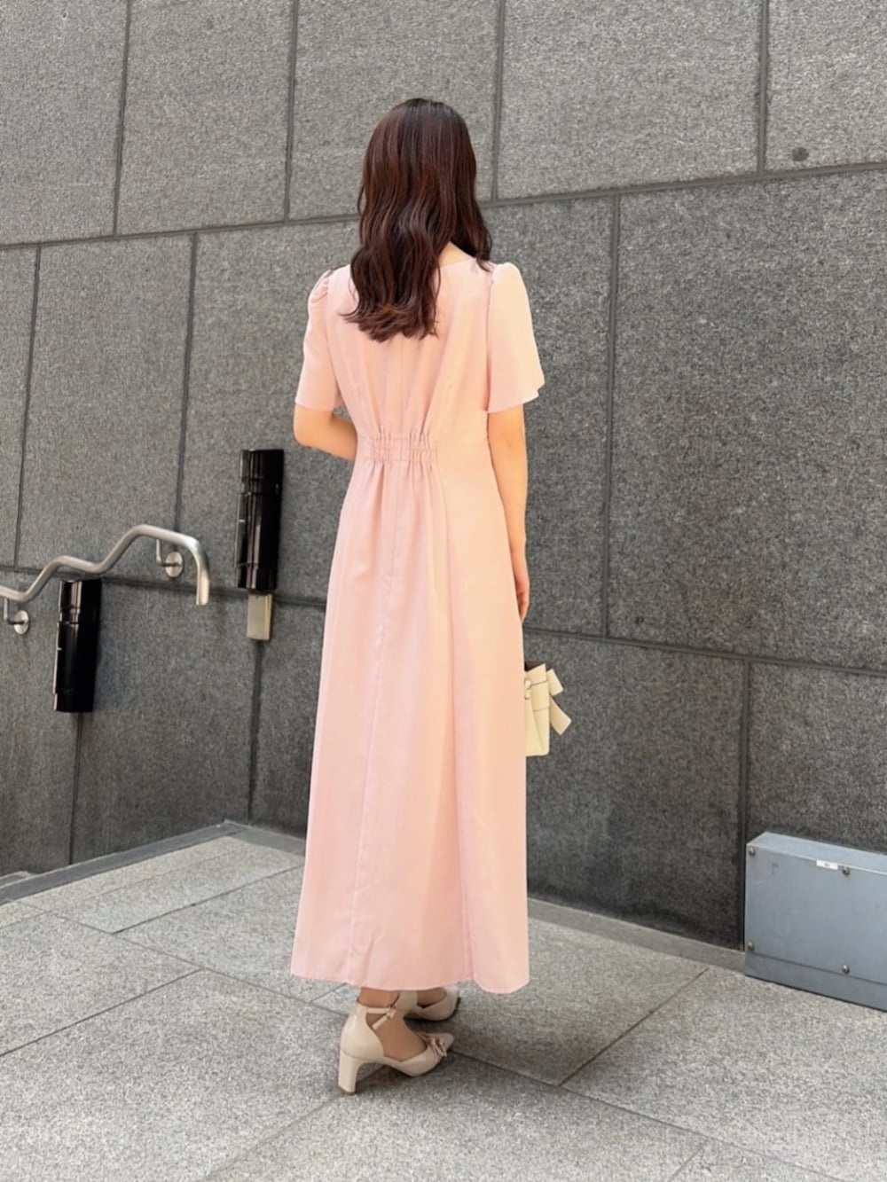 ホワイト系のショルダーバッグ、ベージュ系のパンプス、ピンク系のワンピースを着用したレディースの春コーディネートの3枚目の写真