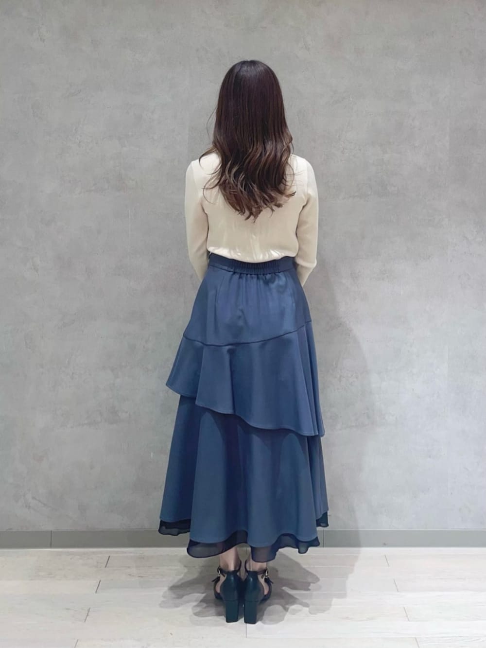 ブルー系のショルダーバッグ、ホワイト系のニット/セーター、グレー系のスカートを着用したレディースの春コーディネートの3枚目の写真