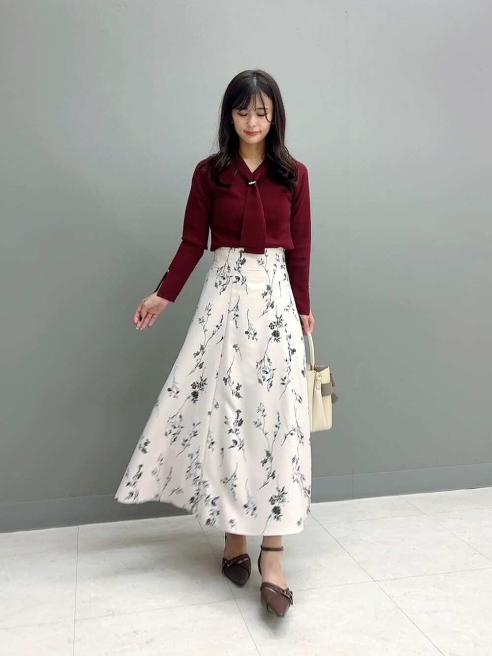 ブラウン系のパンプス、レッド系のニット/セーター、ベージュ系のスカートを着用したレディースの秋コーディネートの2枚目の写真