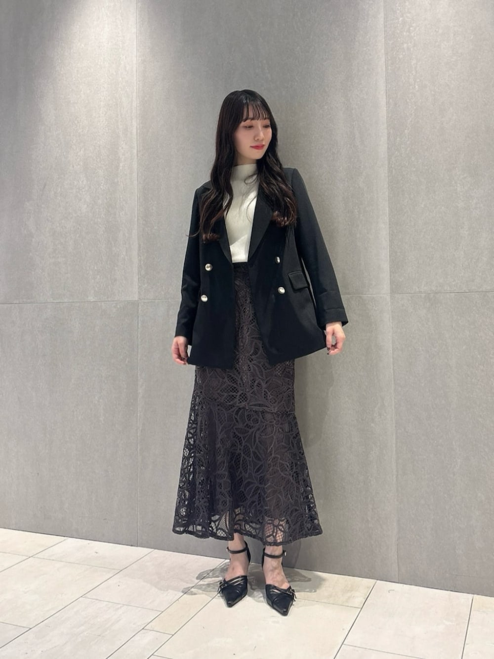 ブラック系のパンプス、ブラック系のテーラードジャケット、ホワイト系のニット/セーターを着用したレディースの秋コーディネートの2枚目の写真