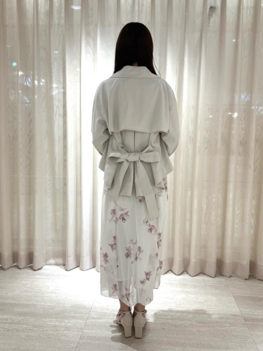 ベージュ系のパンプス、ピンク系のショルダーバッグ、ホワイト系のトレンチコートを着用したレディースの冬コーディネートの3枚目の写真