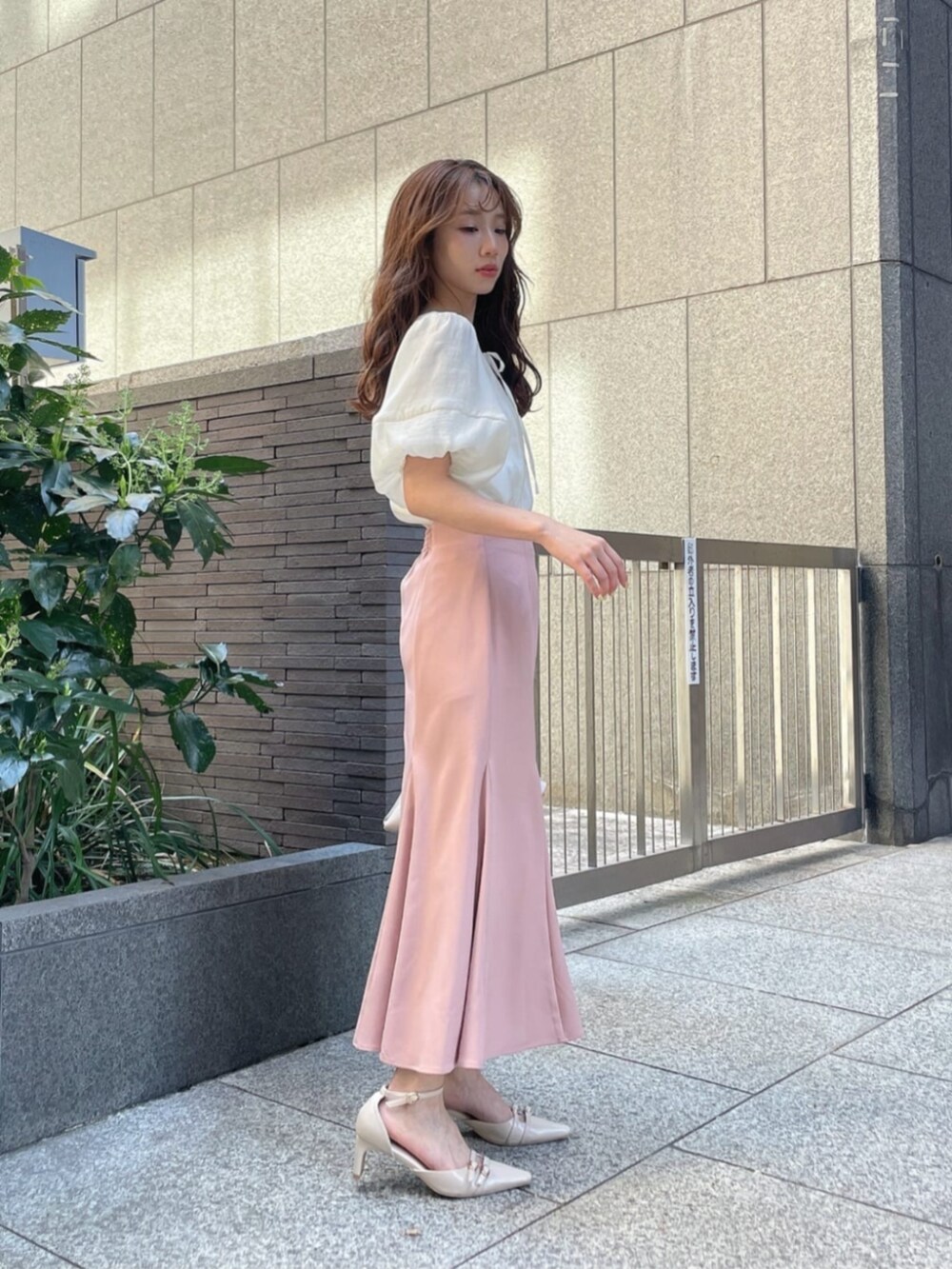 ブラック系のパンプス、ホワイト系のシャツ/ブラウス、ピンク系のスカートを着用したレディースの春コーディネートの2枚目の写真