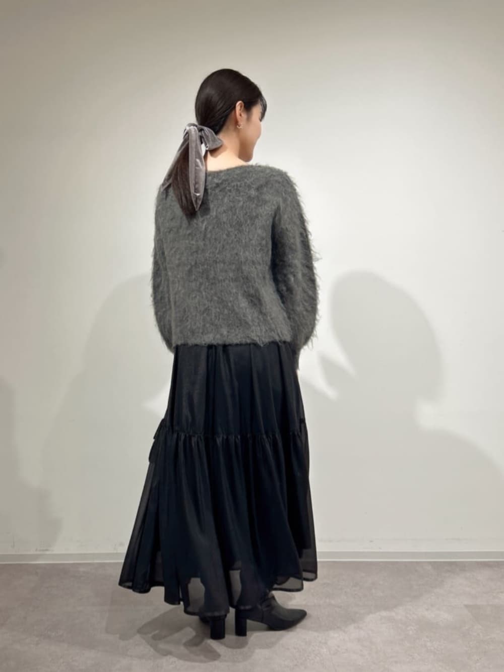 ブラック系のショルダーバッグ、ブラック系のブーツ、グレー系のニット/セーターを着用したレディースの冬コーディネートの2枚目の写真