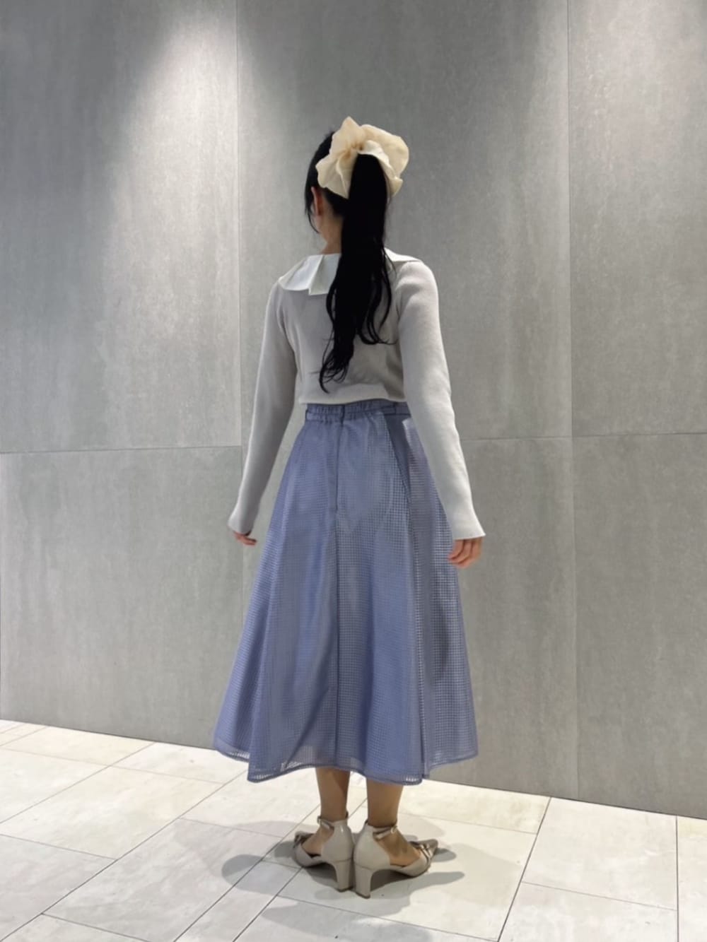 ベージュ系のパンプス、グレー系のニット/セーター、ブルー系のスカートを着用したレディースの春コーディネートの3枚目の写真