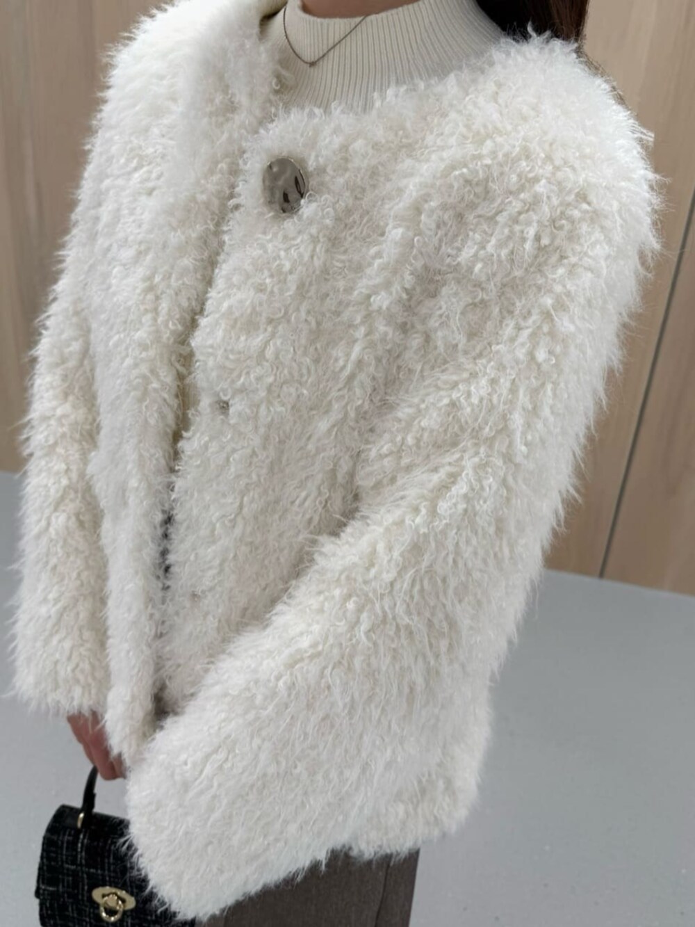 ブラック系のショルダーバッグ、ホワイト系のブルゾン、ホワイト系のニット/セーターを着用したレディースの秋コーディネートの3枚目の写真