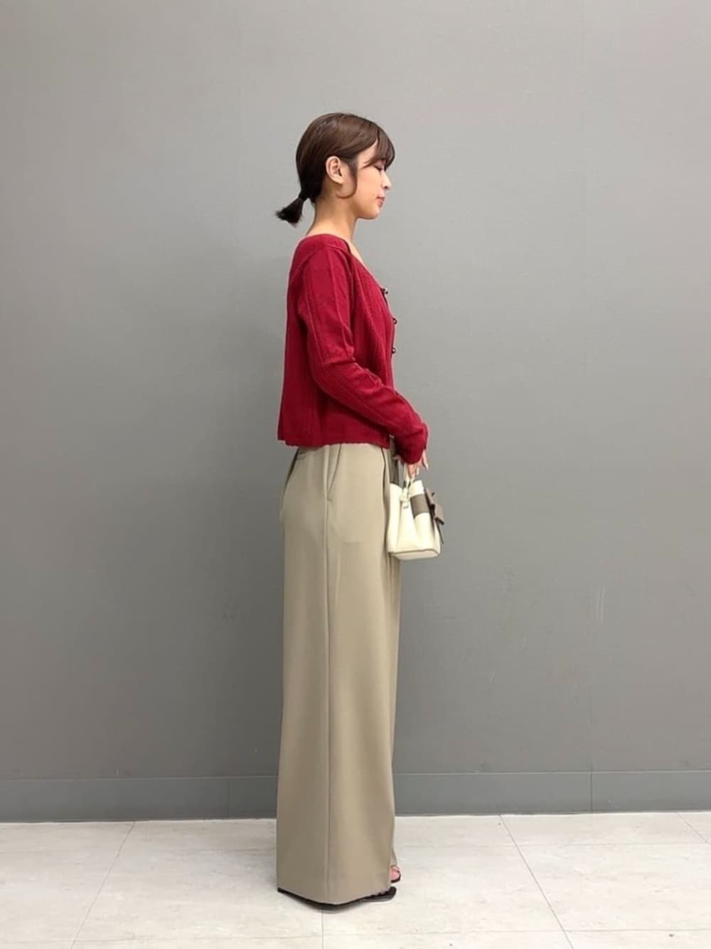 ホワイト系のショルダーバッグ、ベージュ系のその他パンツ、レッド系のアンサンブルを着用したレディースの秋コーディネートの3枚目の写真
