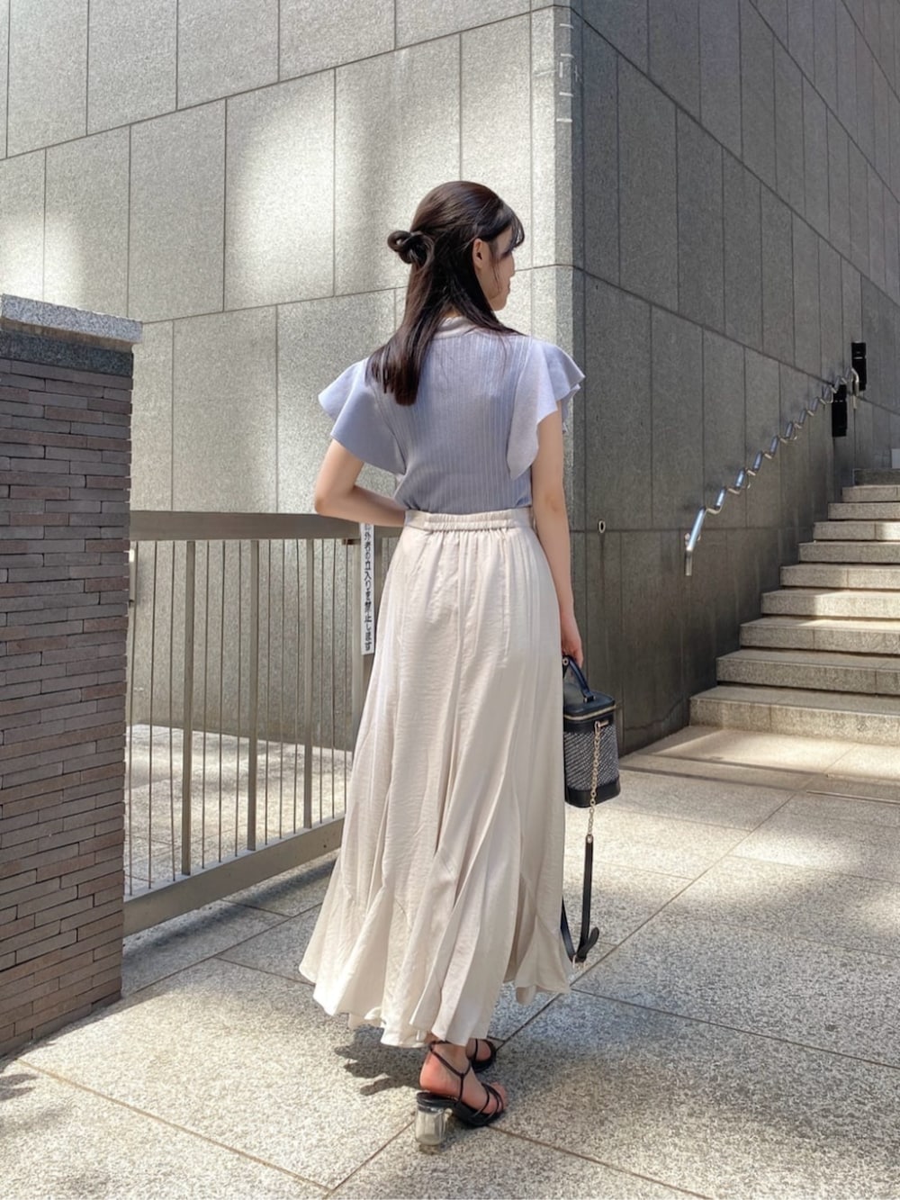 ブラック系のショルダーバッグ、ブルー系のニット/セーター、グレー系のスカートを着用したレディースの夏コーディネートの3枚目の写真