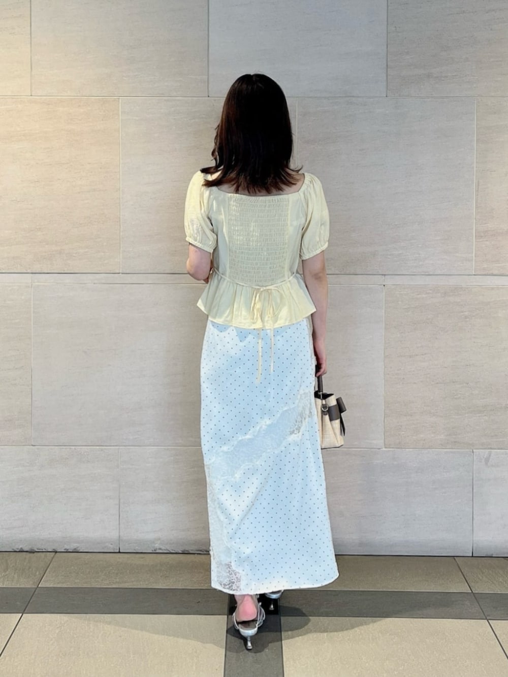 シルバー系のパンプス、ホワイト系のスカート、イエロー系のシャツ/ブラウスを着用したレディースの夏コーディネートの3枚目の写真