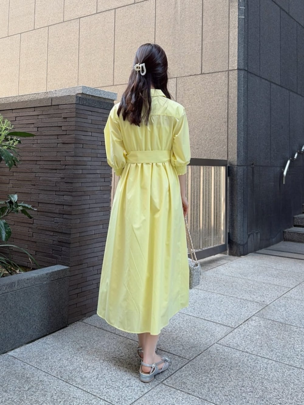 ブラック系のショルダーバッグ、イエロー系のワンピース、シルバー系のパンプスを着用したレディースの春コーディネートの3枚目の写真