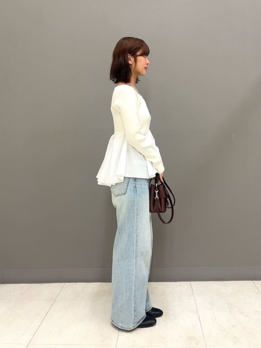 ブラウン系のショルダーバッグ、ブルー系のデニムパンツ、ホワイト系のニット/セーターを着用したレディースの秋コーディネートの3枚目の写真