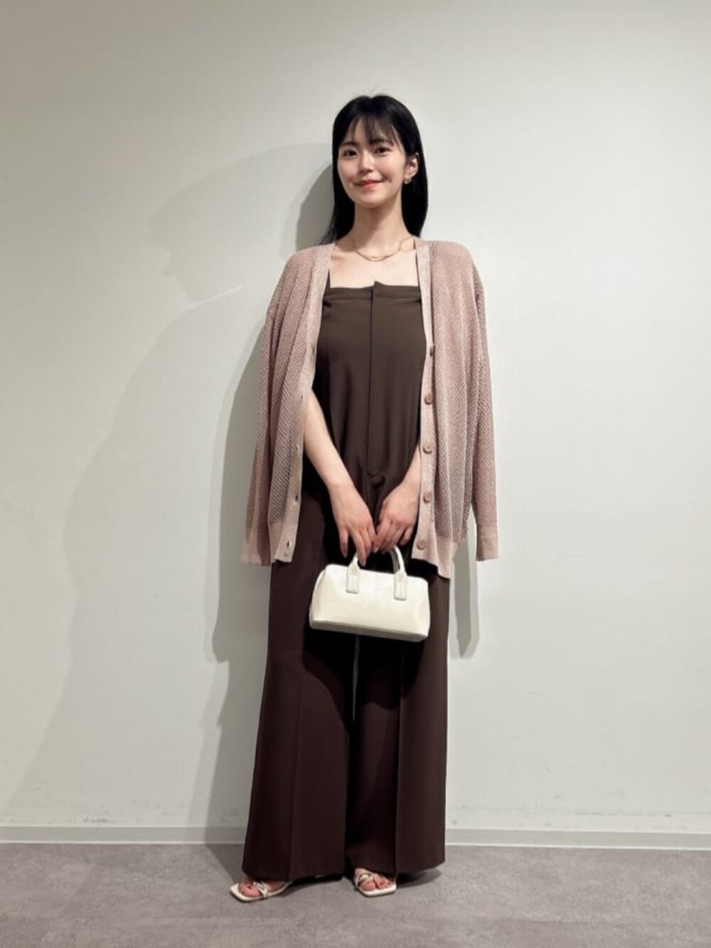 ホワイト系のパンプス、ホワイト系のトートバッグ、ピンク系のニット/セーターを着用したレディースの夏コーディネートの2枚目の写真