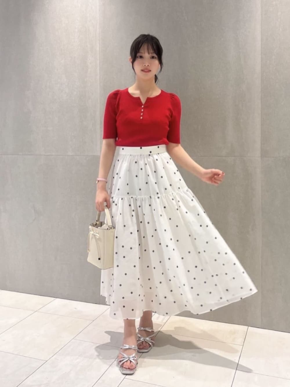 ホワイト系のショルダーバッグ、シルバー系のパンプス、レッド系のニット/セーターを着用したレディースの春コーディネートの2枚目の写真