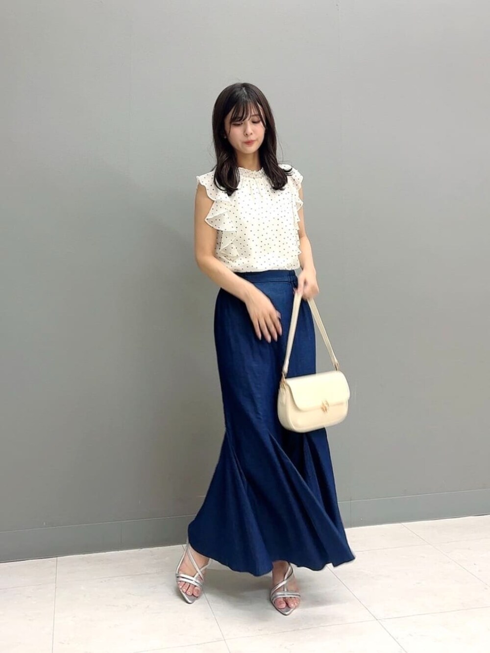 ホワイト系のショルダーバッグ、シルバー系のパンプス、ホワイト系のシャツ/ブラウスを着用したレディースの夏コーディネートの2枚目の写真