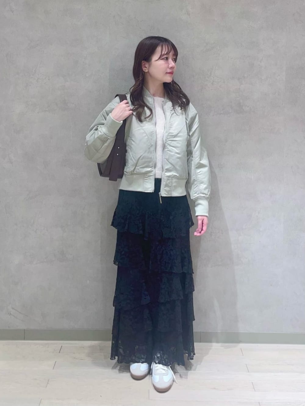 ブラック系のスカート、ブラウン系のハンドバッグ、グリーン系のブルゾンを着用したレディースの冬コーディネートの3枚目の写真