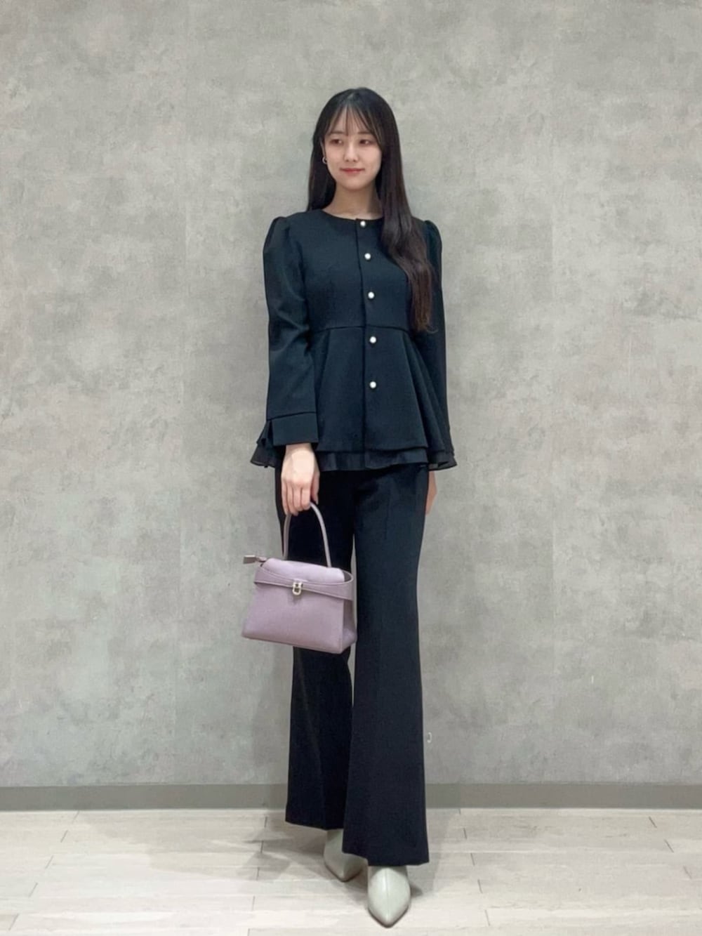 パープル系のトートバッグ、ブラック系のセットアップ、ブラック系のその他パンツを着用したレディースの冬コーディネートの2枚目の写真