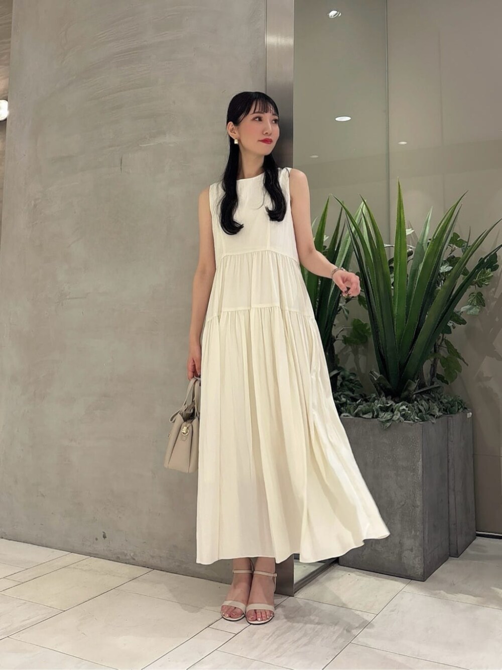 ベージュ系のショルダーバッグ、ホワイト系のワンピースを着用したレディースの夏コーディネートの3枚目の写真