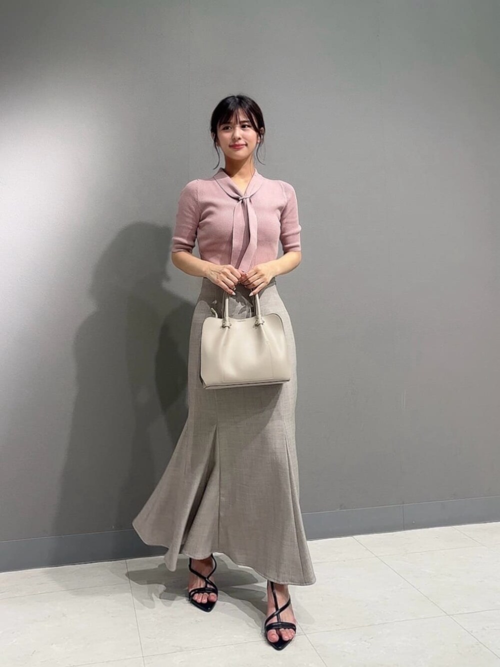 ブラウン系のスカート、ブラック系のパンプス、ピンク系のニット/セーターを着用したレディースの夏コーディネートの3枚目の写真