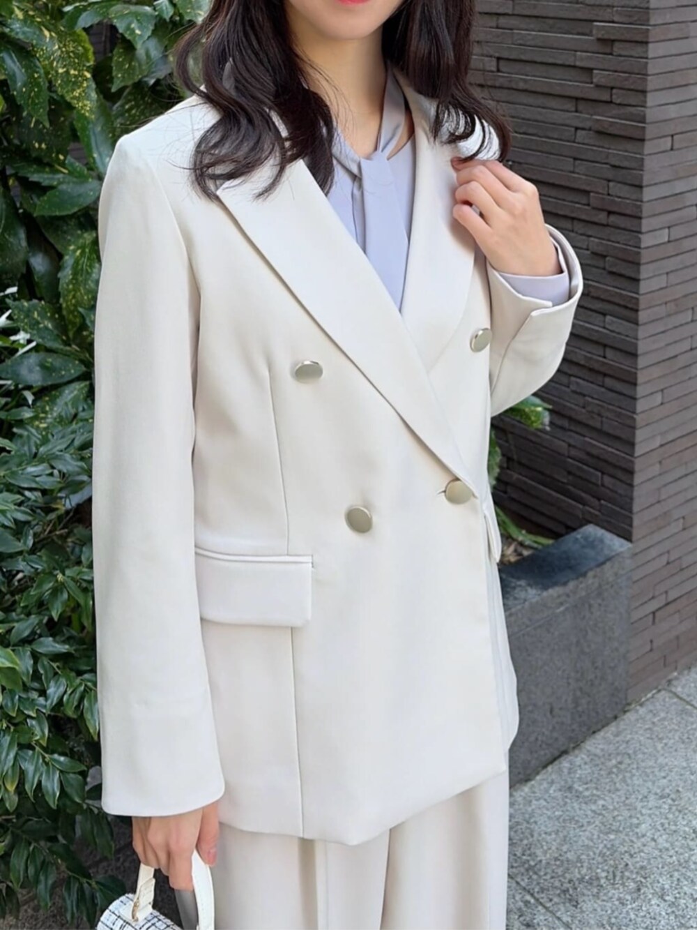 ホワイト系のショルダーバッグ、ブラック系のパンプス、ホワイト系のテーラードジャケットを着用したレディースの冬コーディネートの2枚目の写真