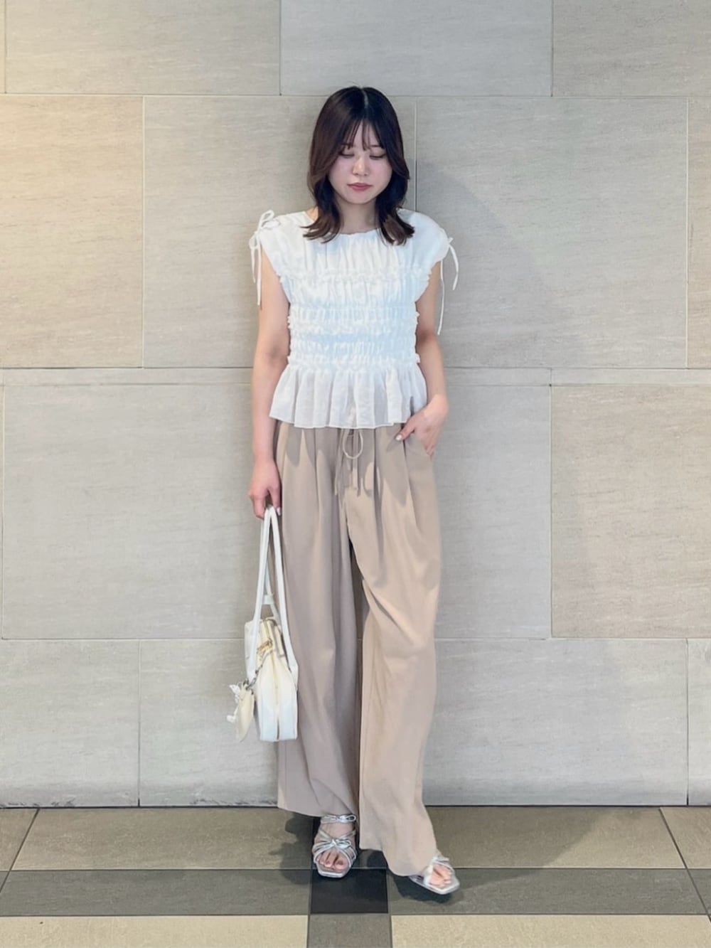 ホワイト系のショルダーバッグ、シルバー系のパンプス、ホワイト系のシャツ/ブラウスを着用したレディースの夏コーディネートの2枚目の写真