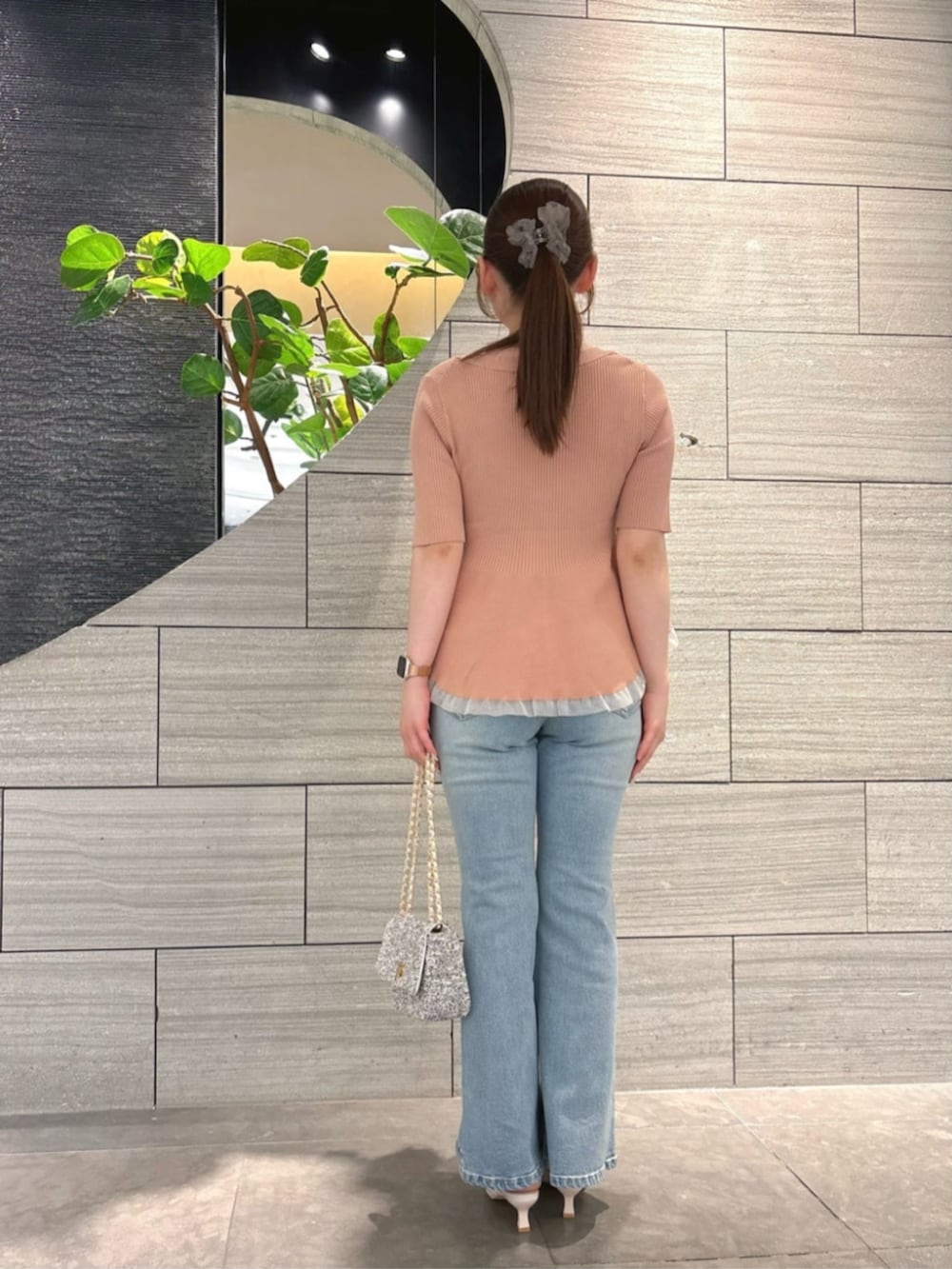 ブラック系のショルダーバッグ、ピンク系のニット/セーター、ブルー系のデニムパンツを着用したレディースの春コーディネートの3枚目の写真