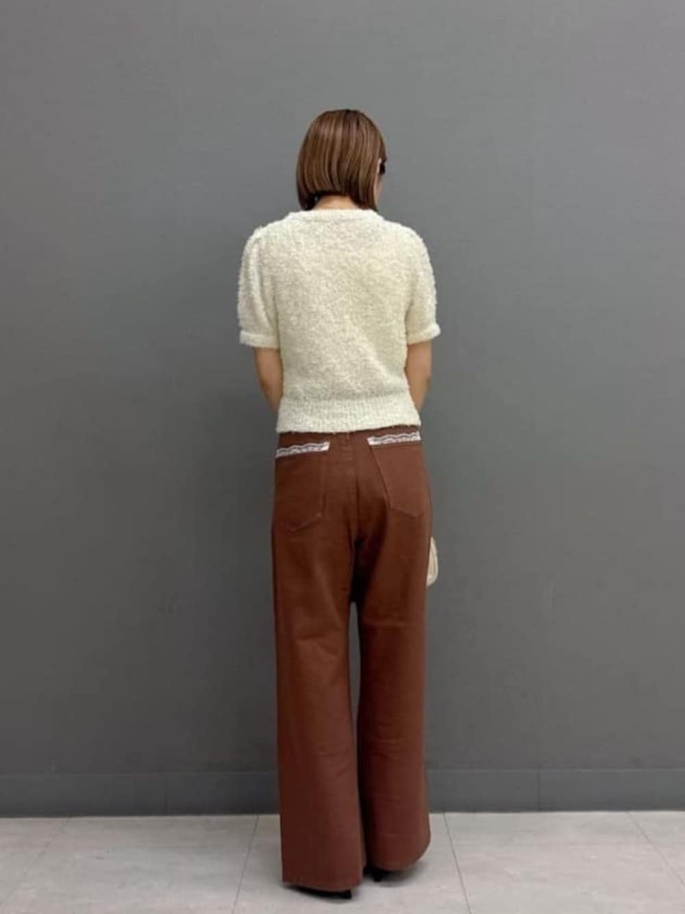 ブラウン系のデニムパンツ、ホワイト系のボストンバッグ、ホワイト系のニット/セーターを着用したレディースの秋コーディネートの3枚目の写真