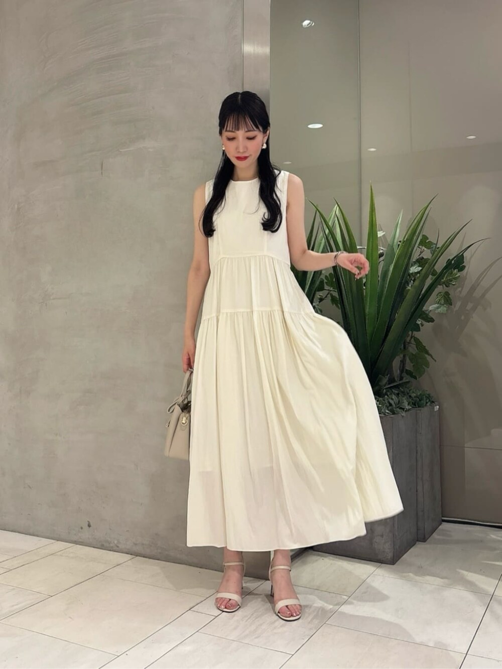 ベージュ系のショルダーバッグ、ホワイト系のワンピースを着用したレディースの夏コーディネートの2枚目の写真