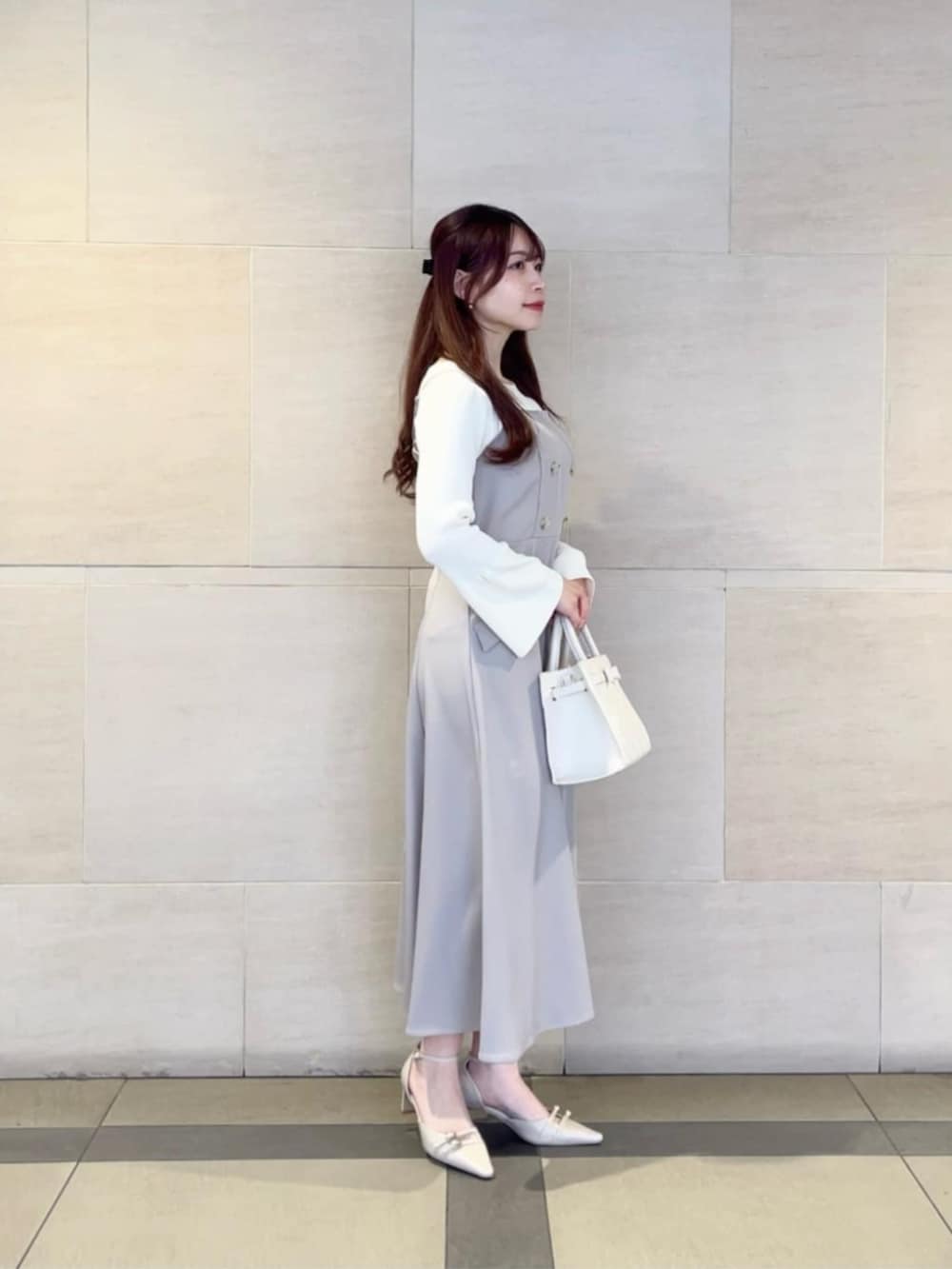 ベージュ系のパンプス、ホワイト系のニット/セーター、ベージュ系のジャンパースカートを着用したレディースの春コーディネートの2枚目の写真