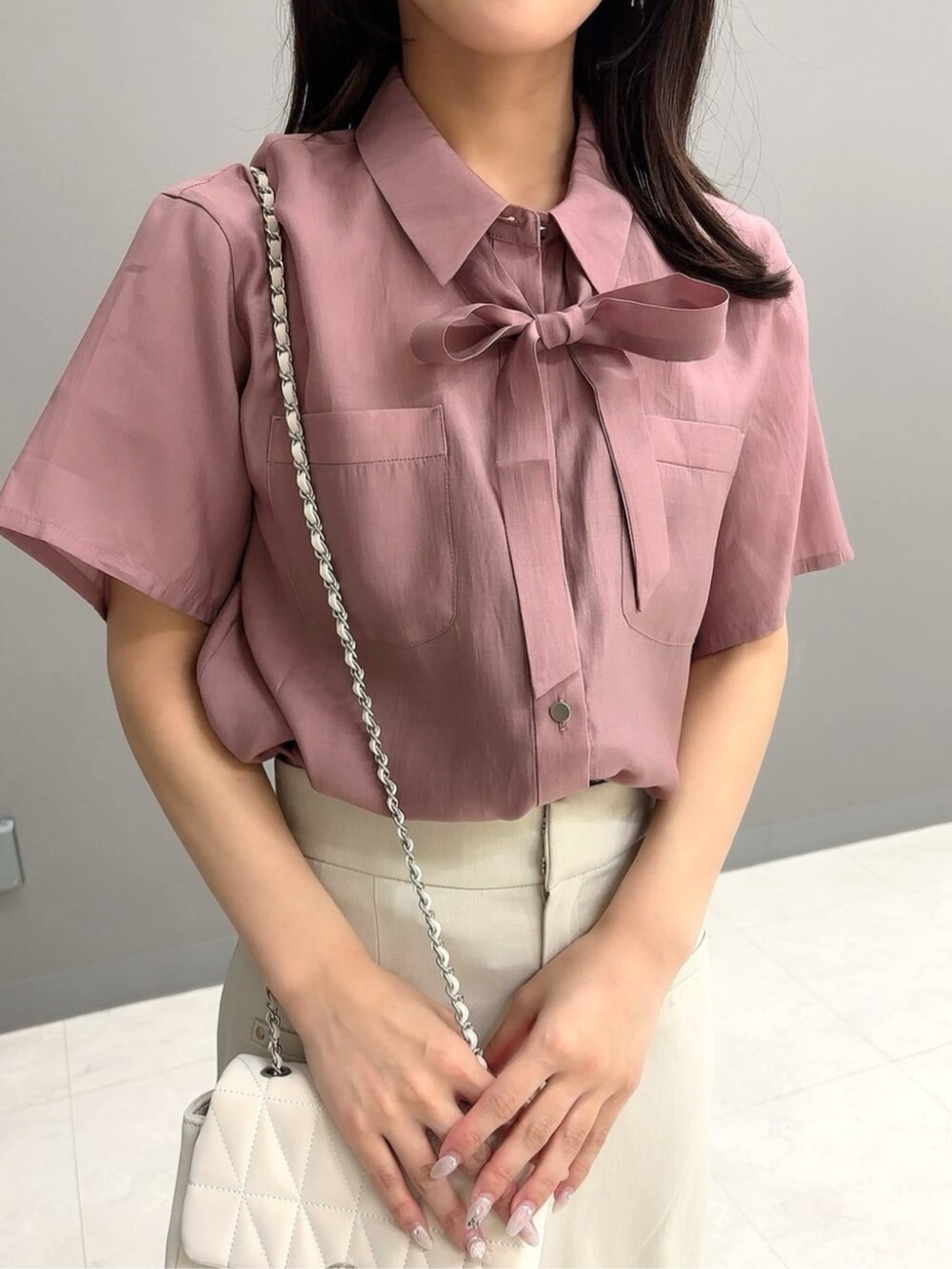 ホワイト系のショルダーバッグ、ピンク系のシャツ/ブラウス、ベージュ系のスカートを着用したレディースの夏コーディネートの3枚目の写真