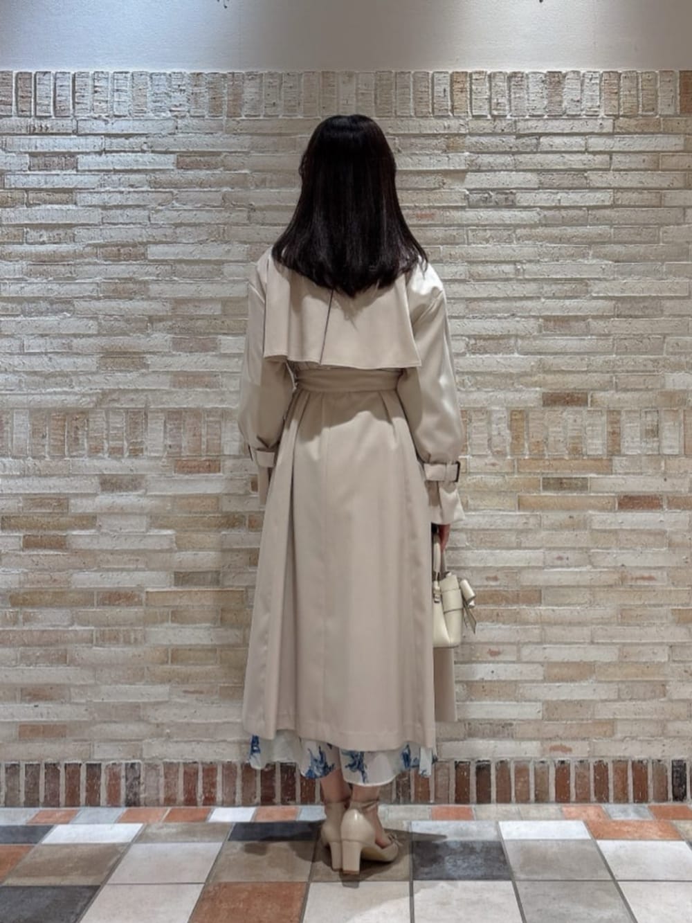 ホワイト系のショルダーバッグ、ベージュ系のトレンチコート、ベージュ系のパンプスを着用したレディースの冬コーディネートの3枚目の写真