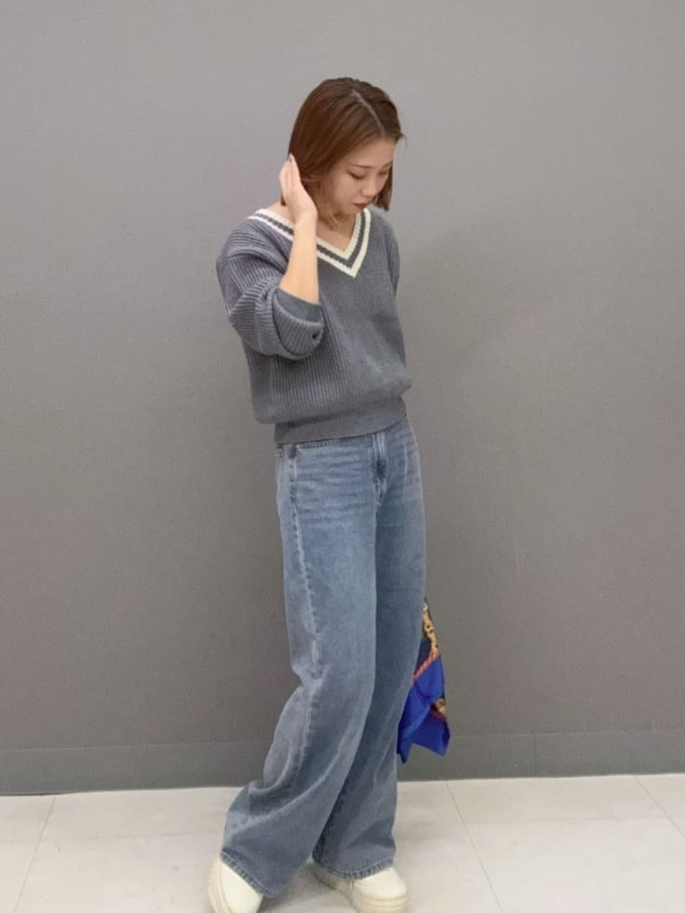 グレー系のニット/セーター、ブルー系のデニムパンツ、ブラック系のハンドバッグを着用したレディースの秋コーディネートの3枚目の写真