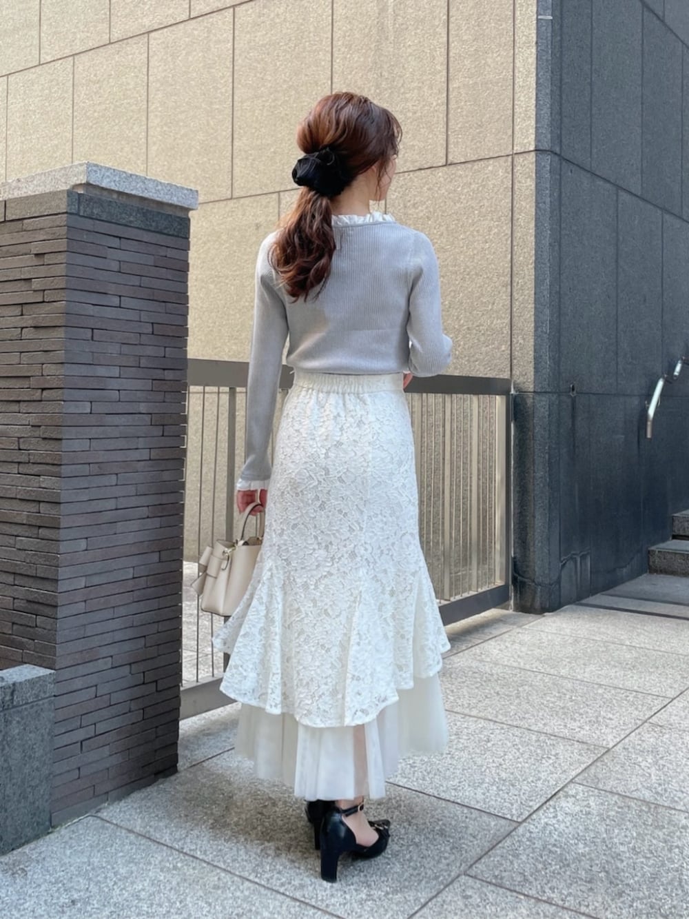 ホワイト系のショルダーバッグ、ブラック系のパンプス、グレー系のニット/セーターを着用したレディースの春コーディネートの3枚目の写真