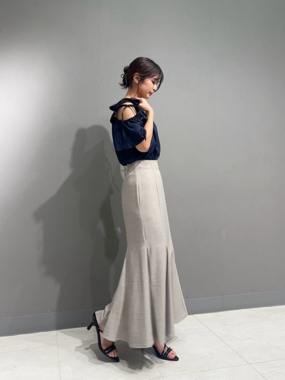 ブラウン系のスカート、ブラック系のパンプス、ブルー系のシャツ/ブラウスを着用したレディースの夏コーディネートの2枚目の写真