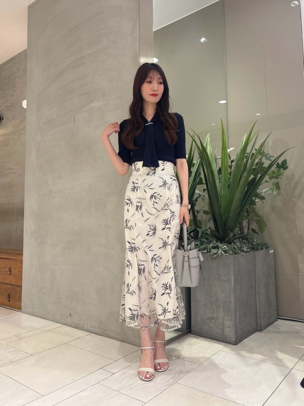 ホワイト系のスカート、ブルー系のニット/セーター、グレー系のショルダーバッグを着用したレディースの夏コーディネートの2枚目の写真