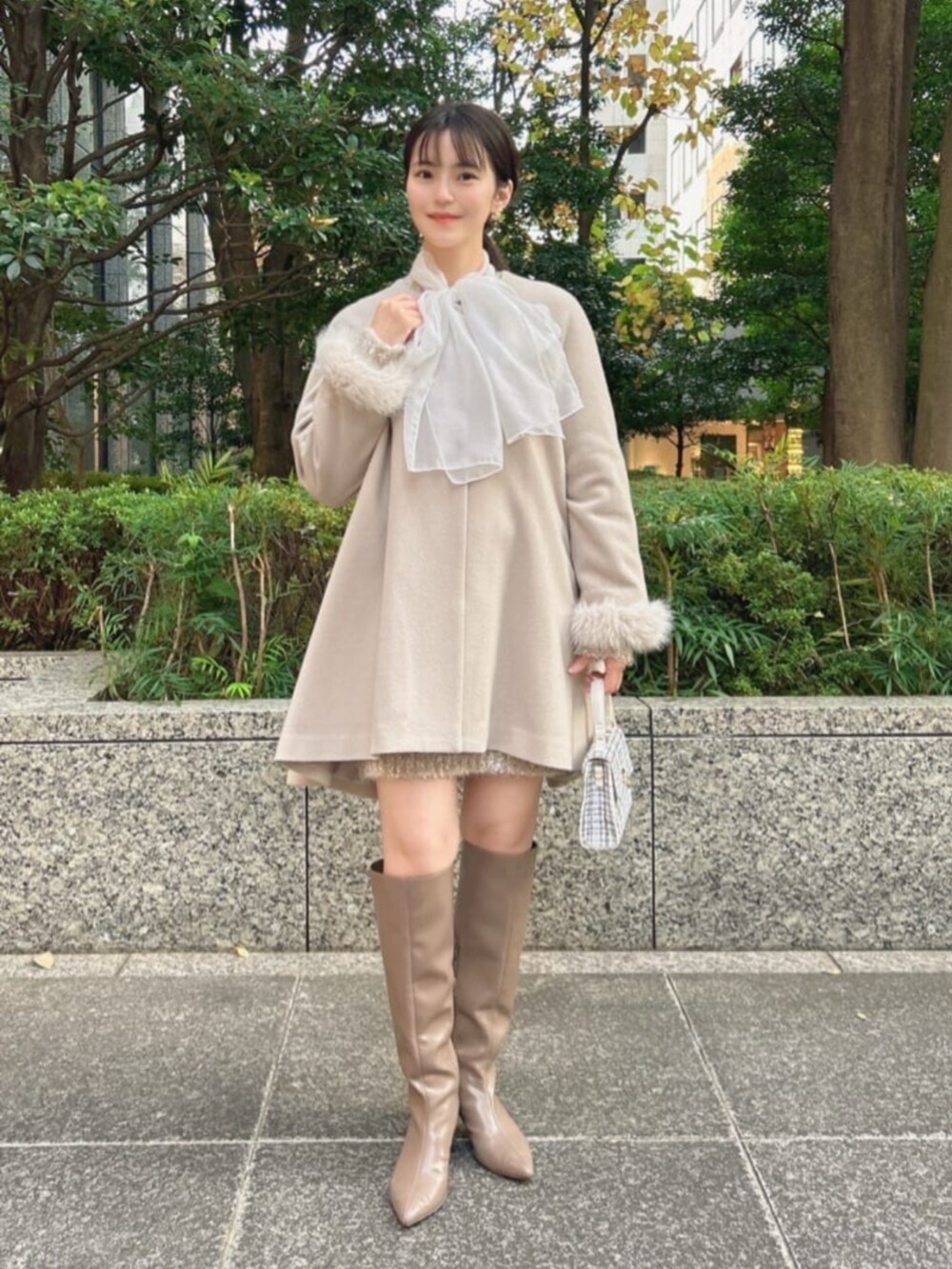 ホワイト系のショルダーバッグ、ブラウン系のブーツ、グレー系のノーカラーコートを着用したレディースの冬コーディネートの3枚目の写真