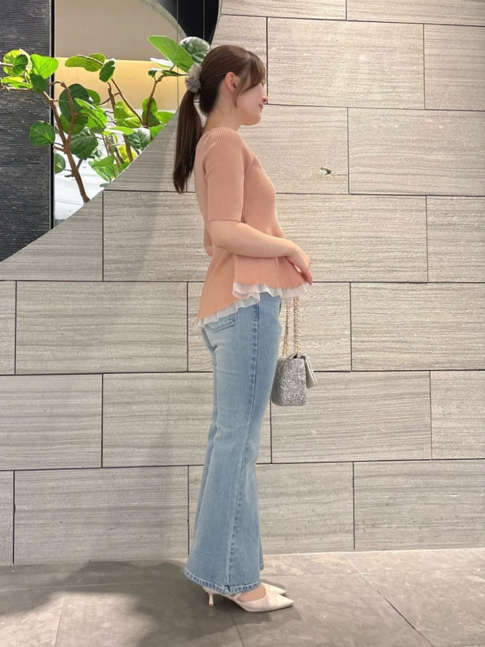 ブラック系のショルダーバッグ、ピンク系のニット/セーター、ブルー系のデニムパンツを着用したレディースの春コーディネートの2枚目の写真