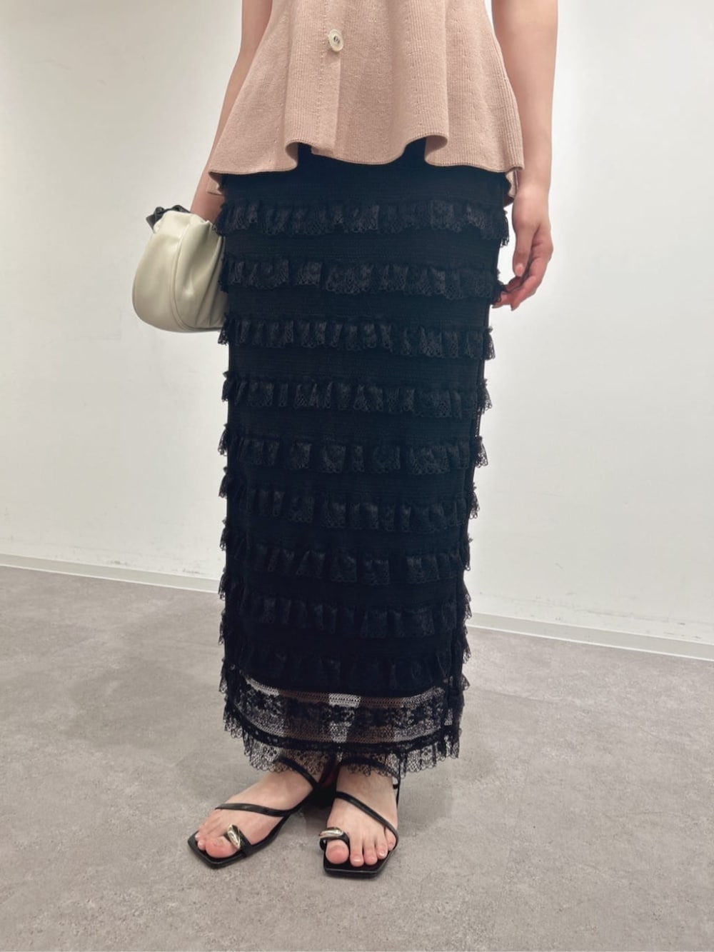 ピンク系のニット/セーター、ブラック系のスカート、ブラック系のパンプスを着用したレディースの夏コーディネートの3枚目の写真