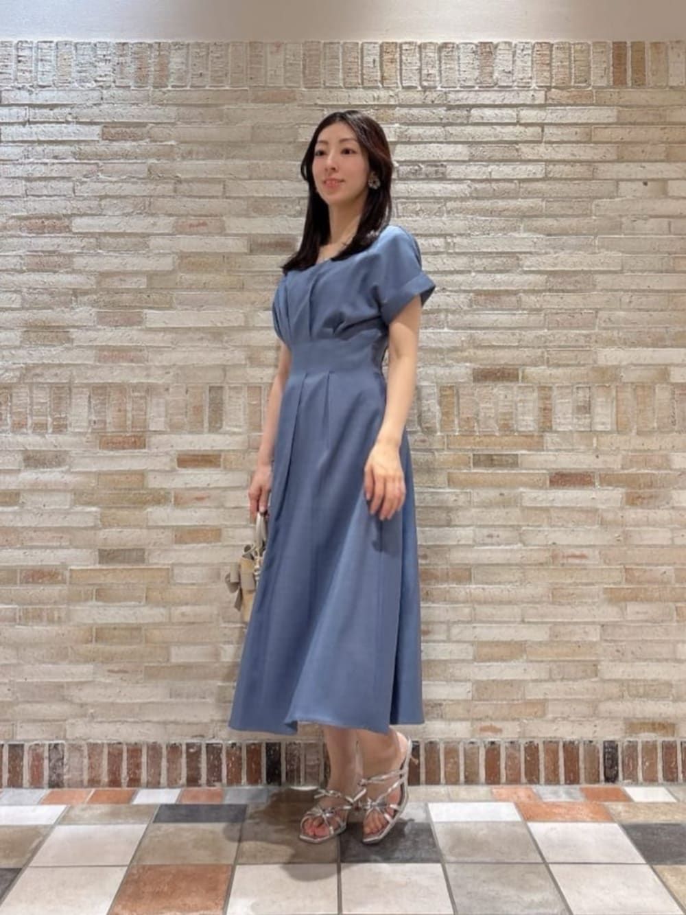 シルバー系のパンプス、ホワイト系のショルダーバッグ、ブルー系のワンピースを着用したレディースの夏コーディネートの2枚目の写真
