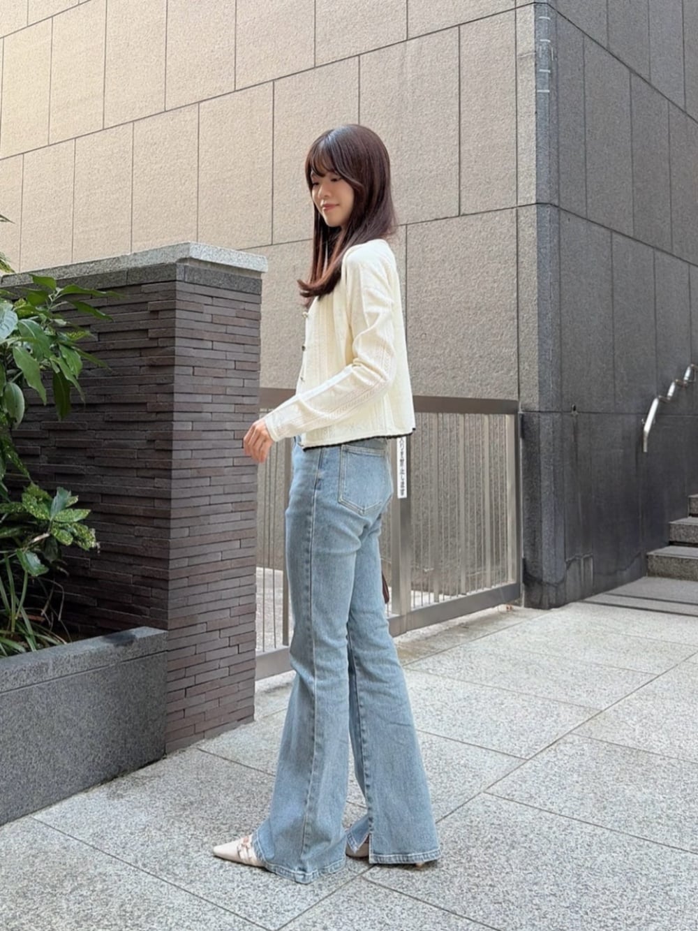 ベージュ系のパンプス、ブルー系のデニムパンツ、ブラウン系のショルダーバッグを着用したレディースの秋コーディネートの2枚目の写真